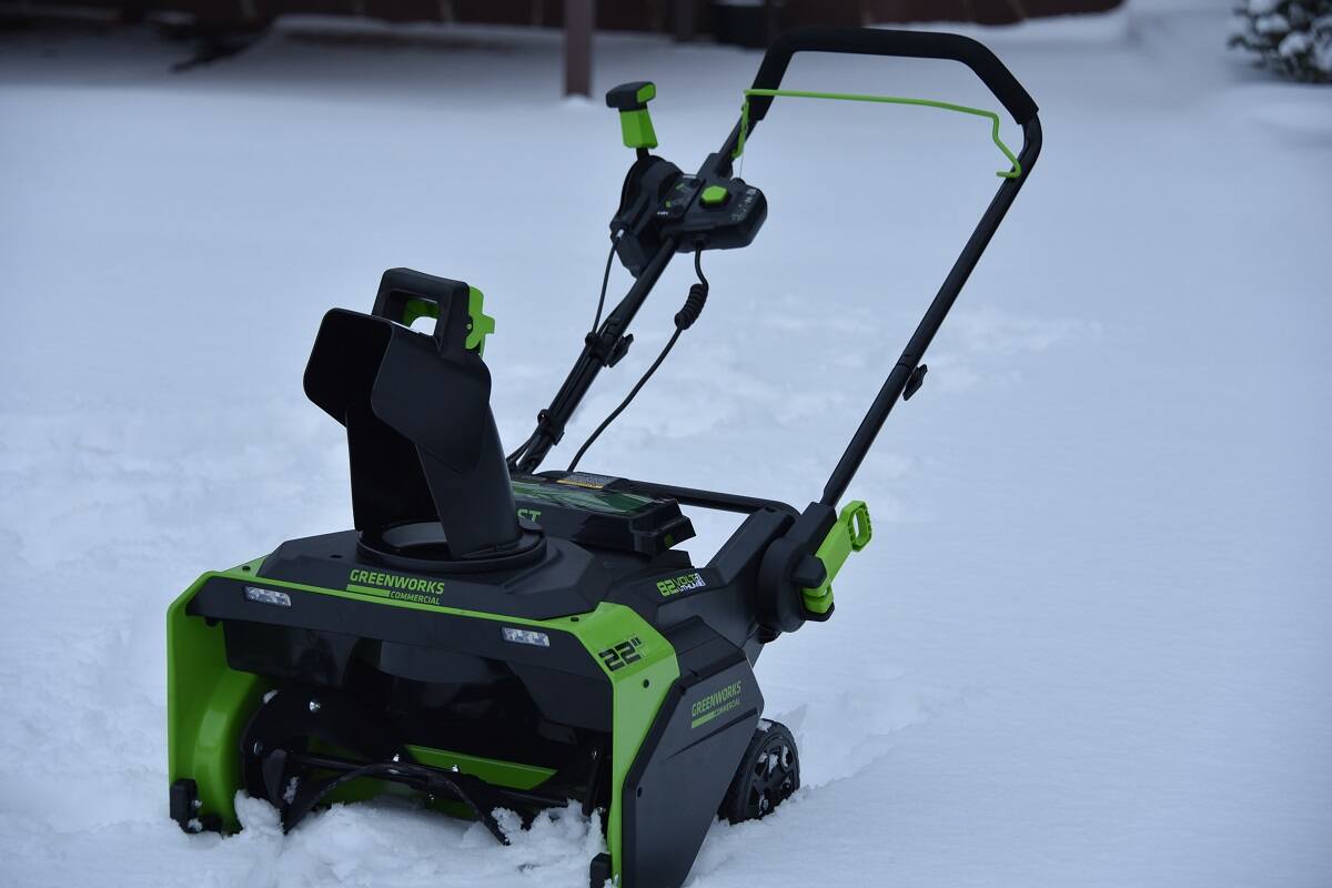 аккумуляторный снегоуборщик Greenworks на фоне снега